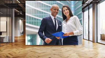 Portrait of a business man and woman of different ethnicity, looking at the camera and smiling, crossing their arms. Concept of: success, finance and team and cooperation. Wall mural