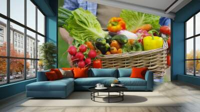 Portrait of a happy young farmer holding fresh vegetables in a basket. On a background of nature The concept of biological, bio products, bio ecology, grown by own hands, vegetarians, salads healthy Wall mural