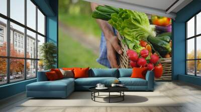 Portrait of a happy young farmer holding fresh vegetables in a basket. On a background of nature The concept of biological, bio products, bio ecology, grown by own hands, vegetarians, salads healthy Wall mural