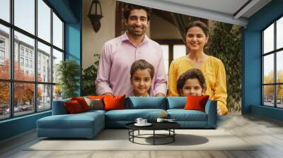 Portrait of Happy Indian Nuclear Family Posing Together Under Natural Light. Gorgeous Parents and Their Cute Two Kids Looking at the Camera, Happy in Their Newly Purchased Home Wall mural