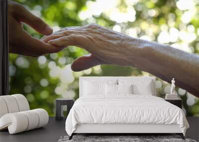 The hand of a young girl (woman) holds the hand of an elderly person, a sign of love, help, faith and support, help to relatives. Concept boarding house, sanatorium, nursing home, help for the elderly Wall mural