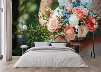 A close up of brides manicured hands holding beautiful bouquet filled with pink and white roses, complemented by delicate greenery and blue flowers, radiating joy and elegance Wall mural