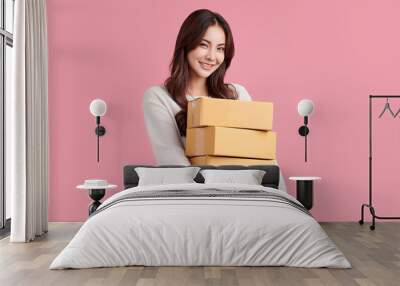 Beautiful Young Asian woman holding parcel box isolated on pink background, Delivery courier and shipping service concept. Wall mural