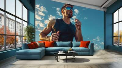 A man running in the sun with a blue shirt and sunglasses Wall mural