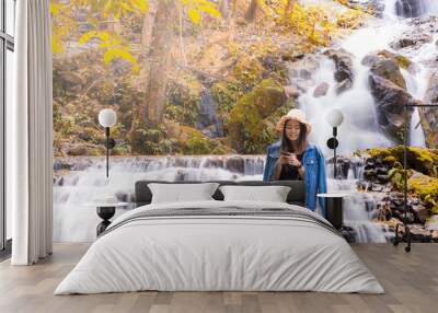 Asian woman alone smiling and waering hat in Autumn waterfalls beautiful scenery in Chiang Mai , Thailand Wall mural