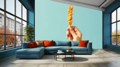 Hand holding a fried chicken stick on blue background Wall mural