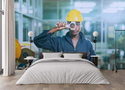 african worker Wearing a yellow safety helmet, he is confidently posing as he picks up the wrench. Wall mural