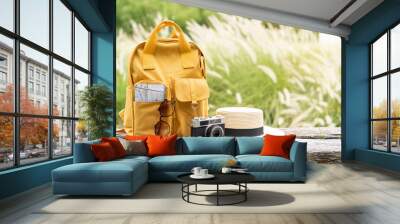 Travel backpack with traveler items on wooden bench with nature background and copy space Wall mural