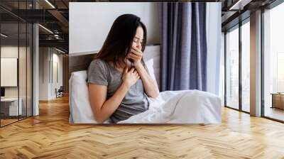 Young Asian woman feels sick and coughing in the bedroom Wall mural