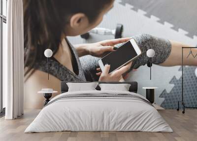 Young asian woman using smartphone in gym Wall mural