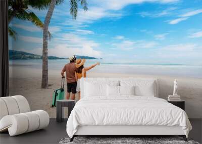 Young couple traveler with luggage relaxing and enjoying at beautiful tropical sand beach, Summer vacation and Travel concept Wall mural