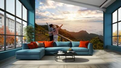 Young couple travelers looking at the sunrise and the sea of mist on the mountain in the morning, Travel lifestyle concept Wall mural