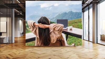 Young woman freelancer traveler working online using laptop and enjoying the beautiful nature landscape with mountain view Wall mural