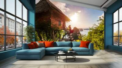 Young woman traveler enjoying and looking beautiful sunrise at the tree house in Nusa Penida island Bali, Indonesia Wall mural