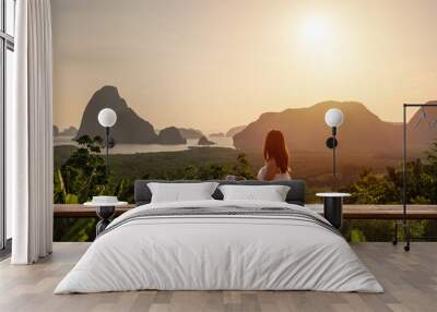 Young woman traveler looking at sunrise over the mountain at samet nang she, Thailand Wall mural