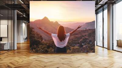 Young woman traveler looking at sunset over the mountain Wall mural