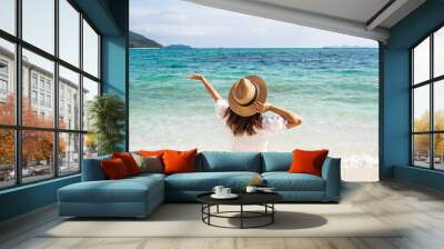 Young woman traveler relaxing and enjoying at beautiful tropical white sand beach with wave foam and transparent sea, Summer vacation and Travel concept Wall mural