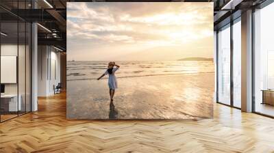 Young woman traveler relaxing and enjoying the beautiful sunset on the tranquil beach, Travel on the summer vacation concept Wall mural