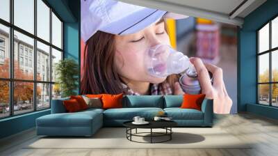 Young woman traveler using oxygen can and breathing for prevent Altitude mountain sickness Wall mural