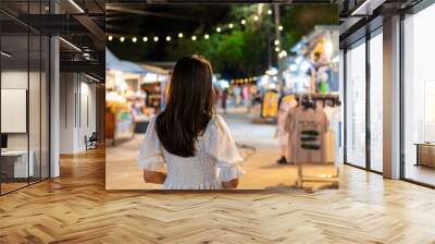 Young woman traveler walking and shopping at night market Wall mural