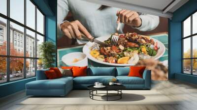 Young woman using knife and fork to cutting meat in restaurant Wall mural