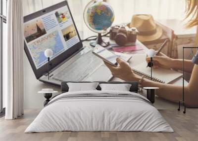 Young women planning vacation trip and searching information or booking an hotel on a smart phone and laptop Wall mural