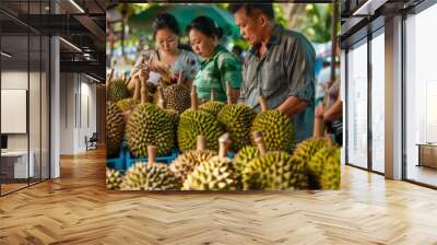 1. A group of people browsing through durian fruits at a market stall, examining the texture and aroma of the tropical fruit. Wall mural