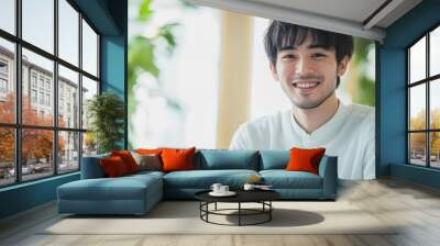 Smiling Young Man Using Laptop in a Bright Workspace Wall mural