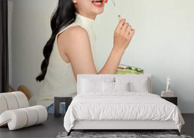 Portrait of pretty young woman eating fresh salad from in modern kitchen. Wellbeing and healthy lifestyle concept Wall mural