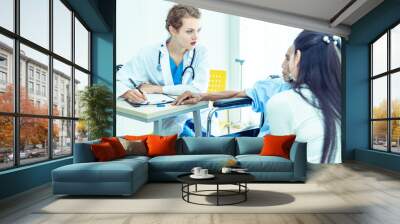 Young professional female doctor helping hands ,explaining diagnosis to senior man patient in medical office at hospital/ clinic .Elderly care medicine, age, health care, cardiology and people concept Wall mural