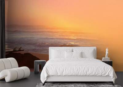 blue sea, fast waves rush to shore, beautiful tropical sunset reflected in water, surfboard lies on stone, ocean is storming, concept trip, paradise island, travel to tropics, surf season, panorama Wall mural