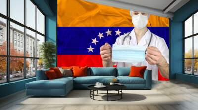 individual medical mask in the hands of a doctor against the background of the national flag of Venezuela, concept of protection against influenza, SARS virus, COVID-19, coronavirus, epidemics Wall mural