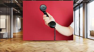 male hand holds a telephone receiver Handset from vintage apparatus on red background, concept of anonymous psychological assistance, helpline number, modern communication technology, call center Wall mural