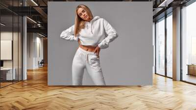 Beautiful blonde woman wear of white set of tracksuit isolated on gray background Wall mural