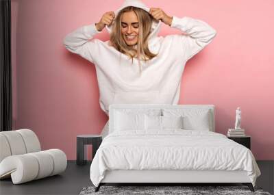 Beautiful smiling blonde woman wear of white set of track suit isolated on pastel background Wall mural