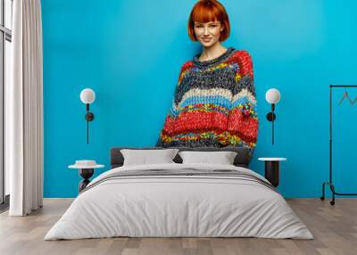 Colorful photo of young female model wear oversize sweater isolated on blue background Wall mural