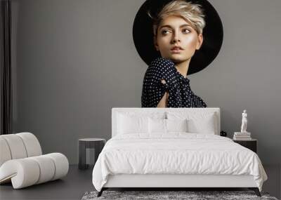 Fashion portrait of female model with blond short hair wear black hat and looking at empty space Wall mural