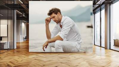 Handsome male model thinking outdoor on a background of lake and mountains Wall mural