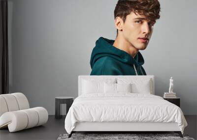 Handsome man wear green hoodie isolated on gray background Wall mural