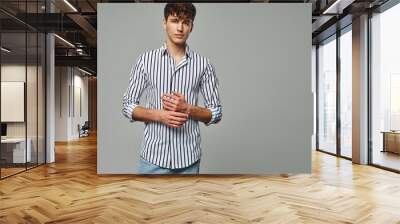 Handsome man wear striped shirt isolated on gray background Wall mural