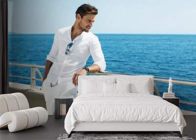 handsome man wearing white clothes posing in sea scenery Wall mural