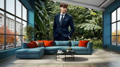 Handsome young man in blue suit posing in garden Wall mural