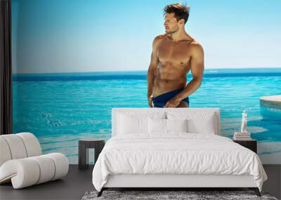 Muscular handsome man posing in swimming pool Wall mural