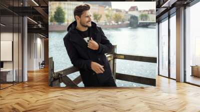 Photo of handsome smiling man in black coat in autumn scenery Wall mural