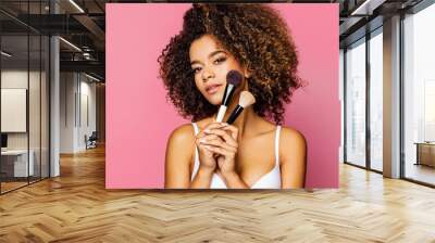 Portrait of the beautiful black woman with make-up brushes near attractive face Wall mural