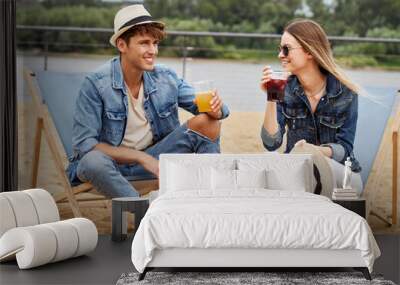 Portrait of young happy beautiful couple sitting on beach chair and drinking ice juice, young couple in love outdoor Wall mural