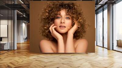 Portrait of young sensual woman with curly hair isolated on brown background Wall mural