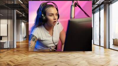 Focused e-sport gamer girl streaming and plays online video game on PC Wall mural