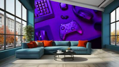 Top view of purple lit keyboard amidst various modern gaming devices Wall mural