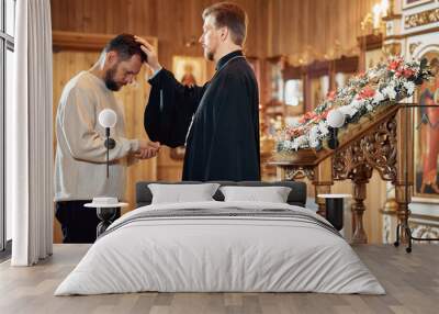 a priest blesses a bearded man in an Orthodox church after a festive church mass Wall mural